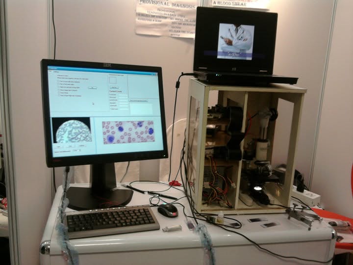 Little Doc prototype with microscope enclosure, monitor showing blood smear analysis UI